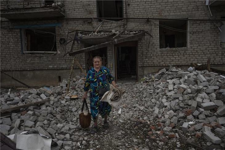 Csasohov Jar, 2022. július 12. Társasházi otthona romjaiból kimentett tárgyakat visz egy nő a donyecki Csasohov Jarban 2022. július 10-én, miután orosz rakétatámadás ért egy lakónegyedet a kelet-ukrajnai városban. MTI/AP
