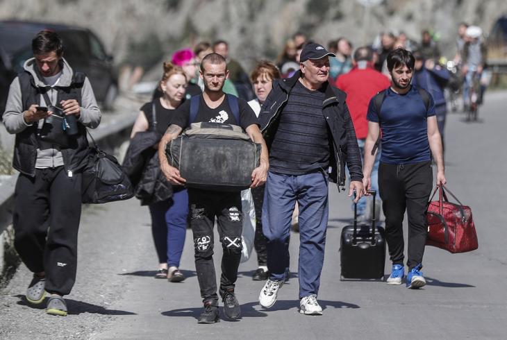 Orosz férfiak és nők csomagjaikkal az úton sétálnak, miután átengedték őket a vámon a grúz-orosz határellenőrzési ponton a grúziai Verkhnii Larsban, 2022. szeptember 27-én. Orosz férfiak ezrei hagyták el Oroszországot, miután Putyin elnök szeptember 21-én a nemzethez intézett televíziós beszédében bejelentette, hogy aláírta az ukrajnai konfliktus miatti részleges mozgósításról szóló rendeletet az Oroszországi Föderációban. Fotó: EPA/Zurab Kurtsikidze