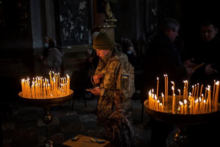 Katonaruhába öltözött ukrán nő imádkozik a Szent Péter és Pál-templomban a nyugat-ukrajnai Lvivben 2022. március 6-án. Fotó: MTI/AP