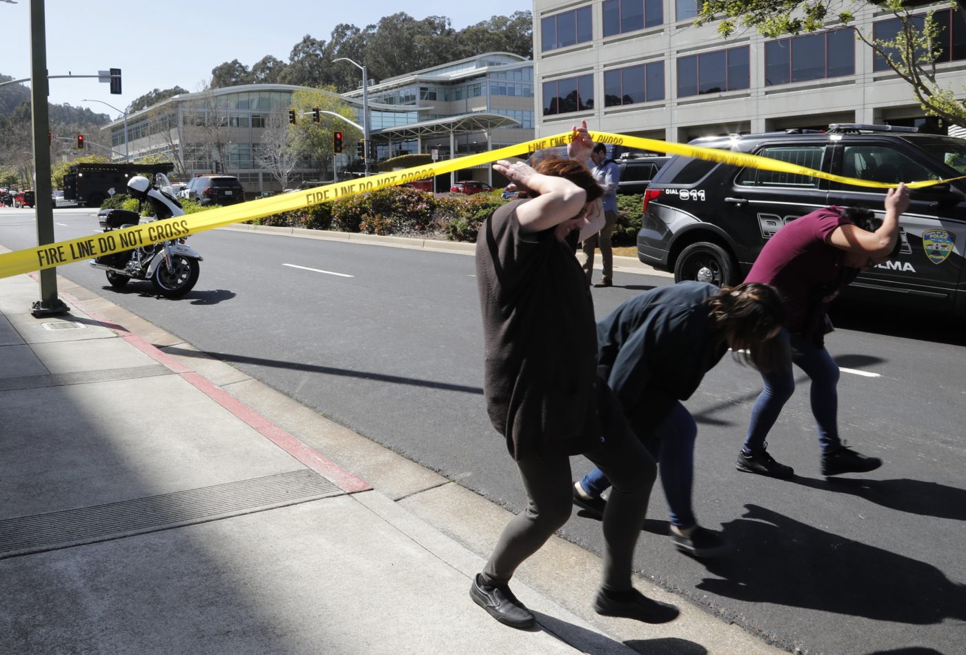 YouTube-alkalmazottak bújnak át a rendőrségi szalag alatt a cég San Bruno-i központjánál. (fotó: MTI/EPA)
