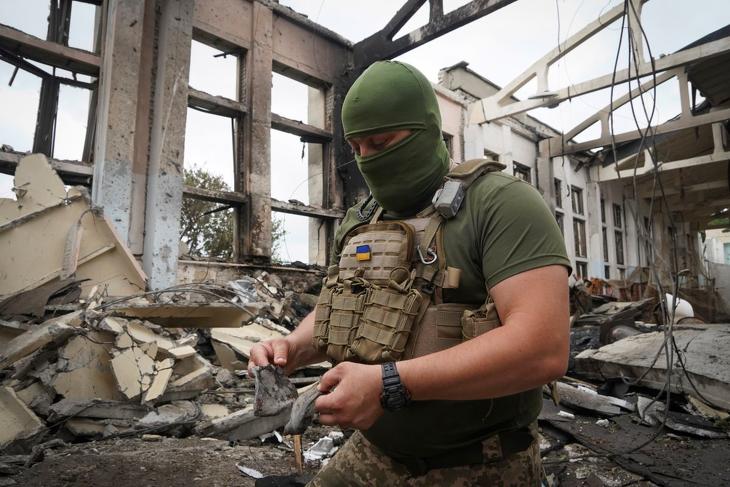 Ukrán katona rakétamaradványokkal a kezében a harkivi Nemzeti Műszaki Egyetem orosz légicsapásban megsemmisült tornatermében 2022. június 24-én. MTI/AP