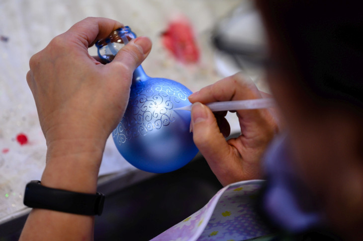 A Szabó Üveg Kft. munkatársa kézzel üvegdíszt fest a tárnoki karácsonyfadísz-manufaktúrában