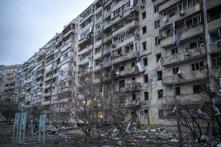 Rakétatámadás során megrongálódott lakóházat néznek emberek Kijevben 2022. február 25-én. (Fotó: MTI/AP/Emilio Morenatti)