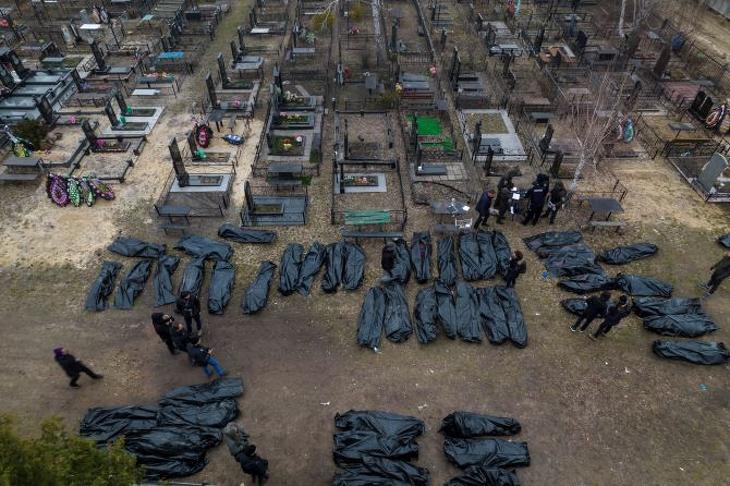 Civilek nejlonzsákban lévő holttesteinek azonosítását végzik rendőrök és hatósági személyek a Kijev melletti Bucsában 2022. április 6-án, mielőtt egy kijevi halottasházba szállítanák őket. Fotó: MTI/AP