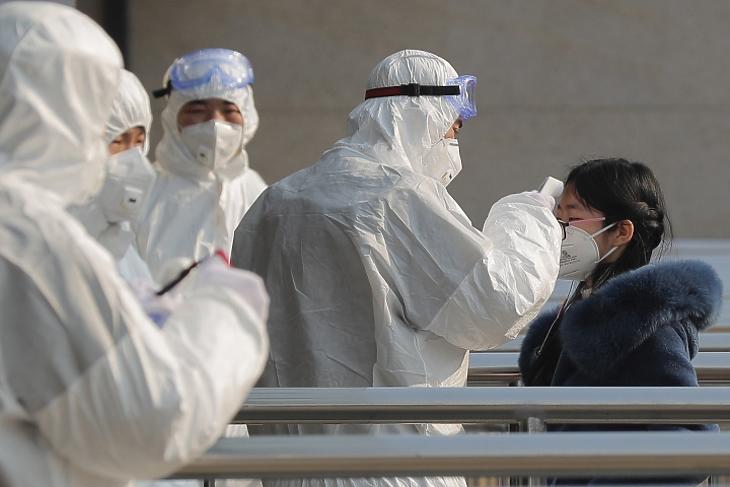 Védőruhába öltözött egészségügyi alkalmazottak egy utas hőmérsékletét vizsgálják egy pekingi metróállomáson 2020. január 25-én. MTI/EPA/Vu Hong