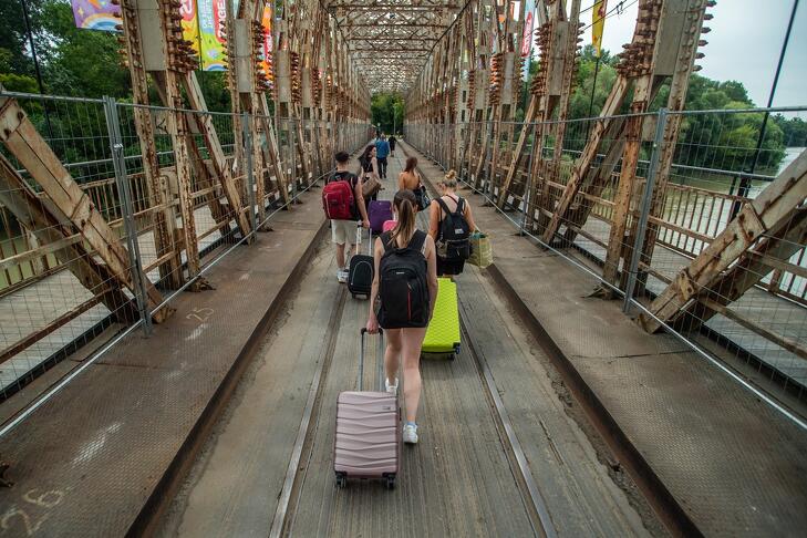 A 29. Sziget fesztiválra tartó fiatalok érkeznek a K-hídon az óbudai Hajógyári-szigetre