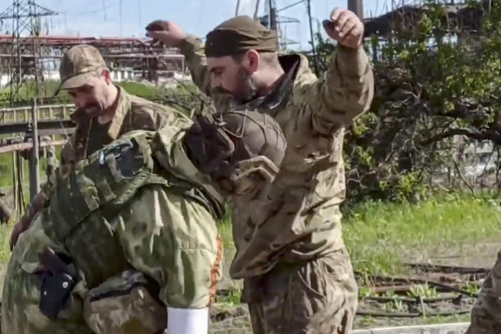Az orosz védelmi minisztérium sajtószolgálata által videófelvételről készített képen egy orosz katona (b) átkutat egy ukrán katonát a mariupoli Azovsztal acélmű területén 2022. május 17-én. A nap folyamán több mint 260 ukrán harcos - sokan közülük sebesültek - hagyhatta el az acélmű területét. Fotó: MTI/EPA/Orosz védelmi minisztérium sajtószolgálata 