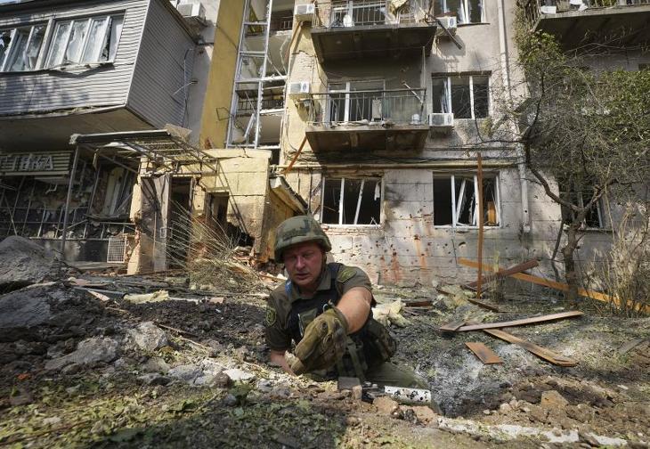 Ukrán katona egy orosz tüzérségi támadásban megrongálódott lakóépület mellett a kelet-ukrajnai Harkivban. Fotó: MTI/AP/Andrij Marienko