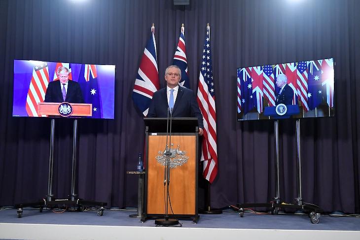 Hibrid sajtótájékoztató - a bal oldali képernyőn Boris Johnson brit miniszterelnök, a jobb oldalin Joe Biden, az USA elnöke, középen pedig Scott Morrison ausztrál miniszterelnök Canberrában 2021. szeptember 16-án az új védelmi szövetség bejelentésekor. Fotó: EPA / Mick Tsikas