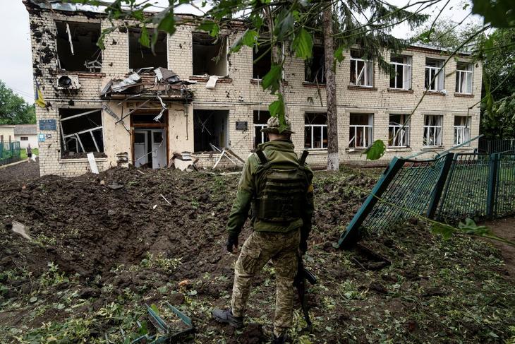Megrongált iskola romjait nézi egy ukrán katona, miután orosz rakétatámadás érte a kelet-ukrajnai Harkiv régióban fekvő települést. Fotó: MTI/AP