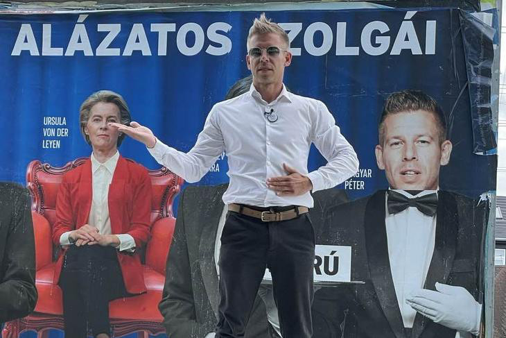Magyar Péter beszél az őt Brüsszel szolgájaként bemutató plakát előtt. Tényleg mindenben be kell állnia a sorba?