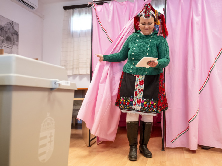 A Rimóci Folklór Manufaktúra és Faluszépítő Egyesület helyi palóc népviseletbe öltözött tagja kilép a szavazófülkéből az országgyűlési választáson a rimóci polgármesteri hivatalban kialakított szavazókörben 2026. április 12-én.