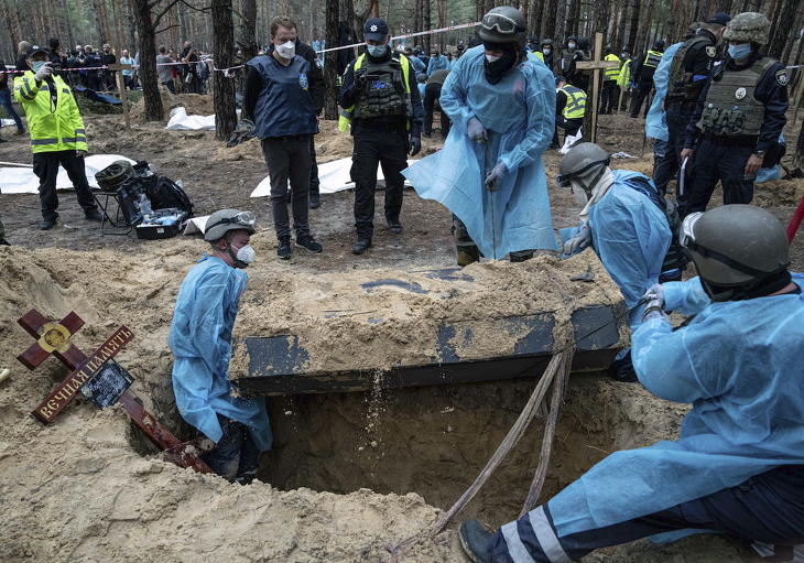 Koporsót emelnek ki a földből az áldozatok exhumálását végző csoport tagjai Izjumnál, a tömegsír felfedezésének másnapján. Fotó: MTI/AP/Jevhen Maloletka