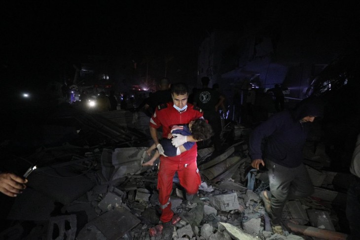 A Palesztin Vöröskereszt munkatársa egy gyerekkel a kezében egy izraeli légitámadás után Gázában, 2023. november. Fotó: Twitter/Palesztin Vöröskereszt