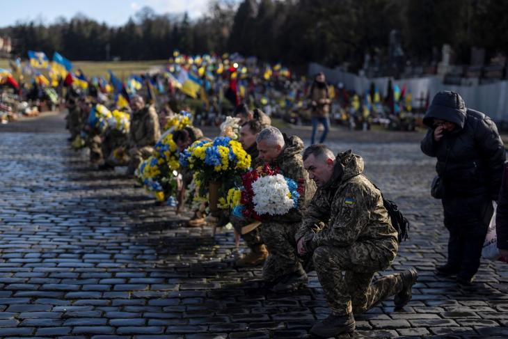 Ukrán katonák térdepelve vesznek búcsút parancsnokuktól, Oleg Vojtyuktól a nyugat-ukrajnai Lviv temetőjében 2023. február 21-én. Vojtyuk a Bahmut településért vívott harcokban szerzett halálos sérülést. Fotó: MTI/AP