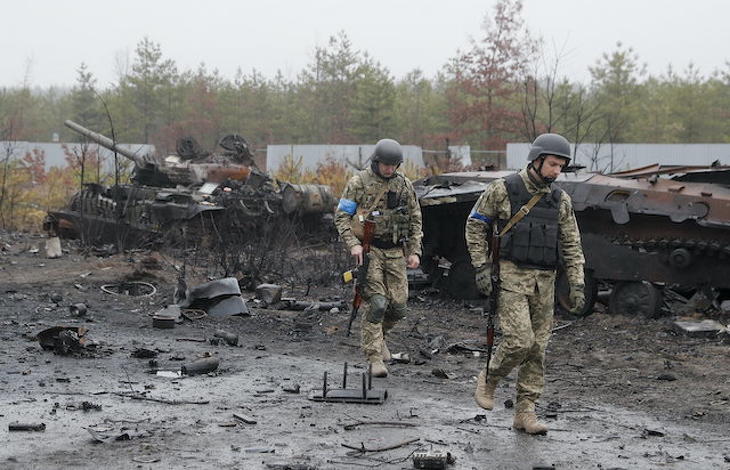 Ukrán katonák egy megsemmisült orosz páncélozott harci jármű roncsa előtt. Ki fogja az ország bztonságát garantálni? Fotó: MTI/EPA/Szerhij Dolzsenko