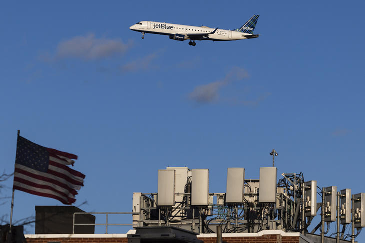 A JetBlue amerikai légitársaság egyik gépe leszálláshoz készül a New York-i LaGuardia repülőtéren, az előtérben távközlési antennák egy háztetőn 2022. január 18-án. (Fotó: MTI/EPA/Justin Lane)