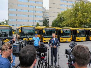 Rétvári Bence a Volán Röszke-Brüsszel feliratú buszai előtt