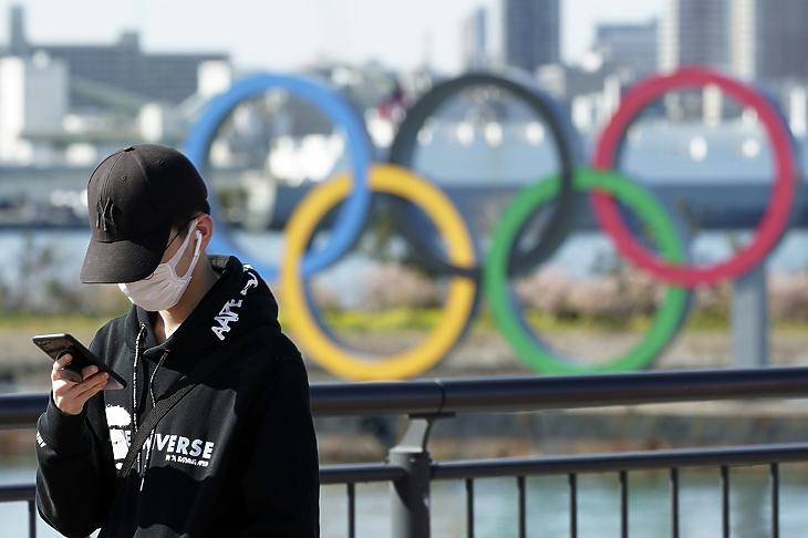 Egészségügyi maszkot viselő fiú az olimpiai játékok szimbóluma, az öt karika előterében, Tokió Odaiba városrészében 2020. március 3-án. MTI/AP/Eugene Hoshiko