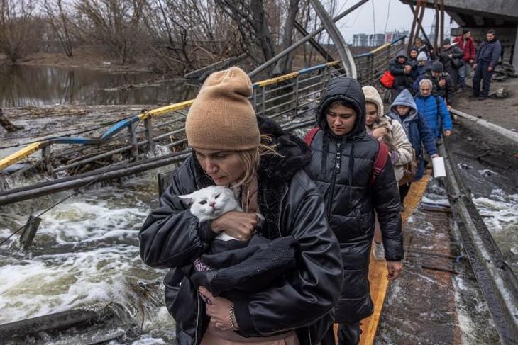 A Kijev közelében lévő Irpinyből menekülő emberek átkelnek egy orosz légicsapásban lerombolt híd alatt kialakított átkelőn, az Irpiny folyónál 2022. március 7-én. Fotó: MTI/EPA