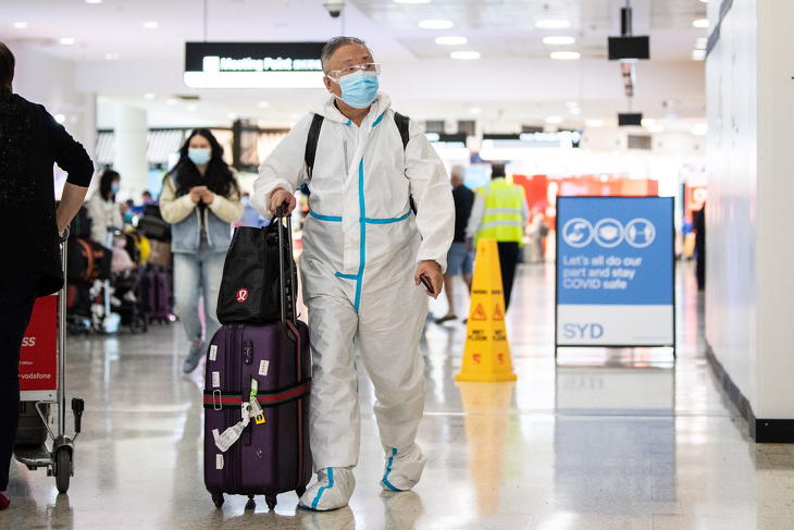 Védőruhát viselő utas érkezik a sydneyi repülőtérre 2021. november 29-én. Az előző hét végén jelentették be, hogy elkezdett terjedni az új koronavírus-variáns, az omikron. (Fotó: MTI/EPA-AAP/James Gourley)