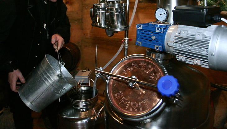 Pálinkafőző szakember hűtővizet önt egy lepárló berendezésbe (MTI Fotó: Varga György)