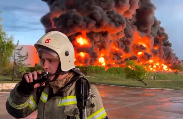 Mihail Razvozsajev szevasztopoli kormányzó Telegram-csatornája által közreadott, videófelvételről készített kép egy tűzoltóról a feltehetően dróntámadás következtében kigyulladt üzemanyagtartállyal a háttérben az Oroszország által annektált Szevasztopolban 2023. április 29-én. A tűzben senki sem sérült meg. Fotó: MTI/AP