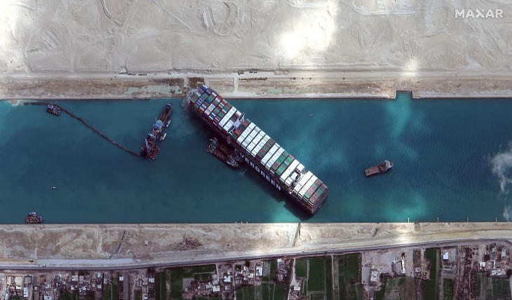 Munkagépekkel és vontatóhajókkal próbálják kiszabadítani a keresztbe fordult és beszorult Ever Given nevű konténerszállítót a Szuezi-csatornában 2021. március 28-án. (Fotó: MTI/EPA/Maxar Technologies)