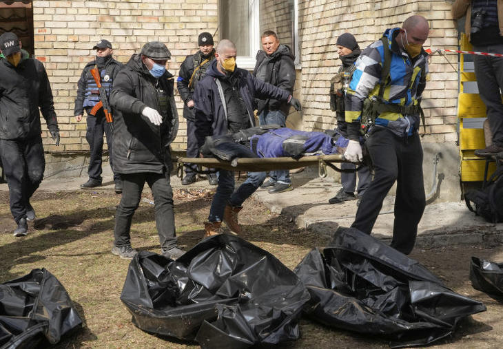 Önkéntesek egy civil holttestét készülnek nejlonzsákba helyezni a Kijev melletti Bucsában 2022. április 4-én. Fotó: MTI/AP/Efrem Lukackij 