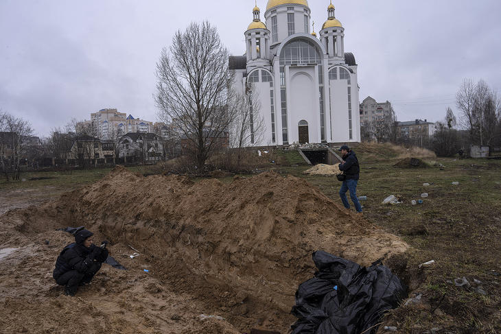Újságírók egy tömegsírt fényképeznek egy templom közelében a Kijev melletti Bucsában 2022. április 3-án. Fotó: MTI/AP/Rodrigo Abd 